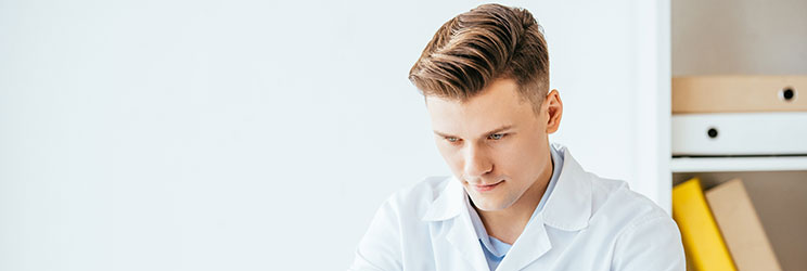 Audioprotesista Audika seduto alla scrivania mentre esamina un test uditivo.