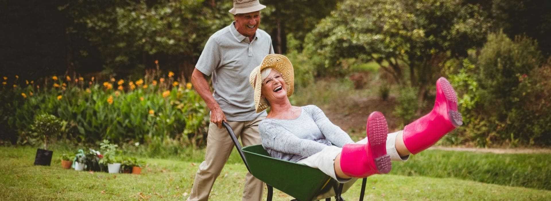 Coppia di anziani che si diverte in giardino, simbolo di benessere e cura dell'udito.