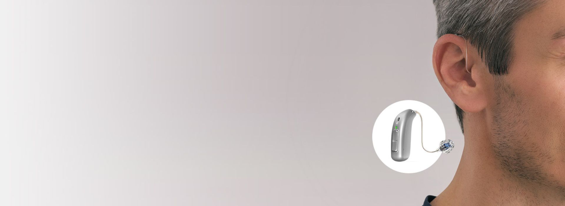 Apparecchio acustico retroauricolare indossato da un uomo con dettaglio evidenziato del dispositivo
