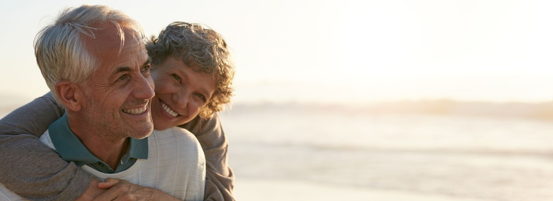 Coppia di anziani abbracciata al tramonto sulla spiaggia
