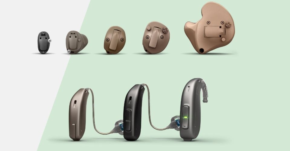 Una gamma di apparecchi acustici in diversi modelli: intrauricolari marroni in alto, retroauricolari moderni e sottili in basso. Sfondo verde chiaro e bianco.