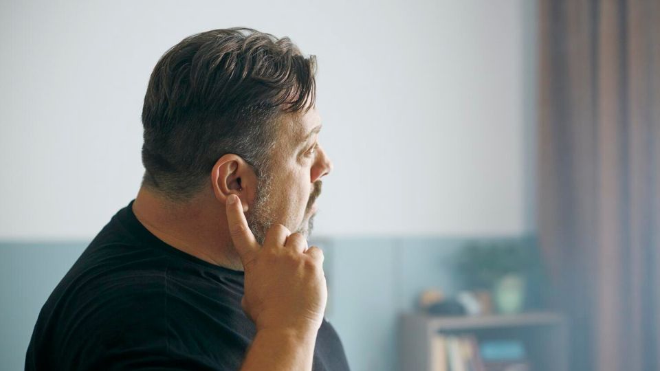 Persona che indica l'orecchio, simbolo di acufene o problemi uditivi.