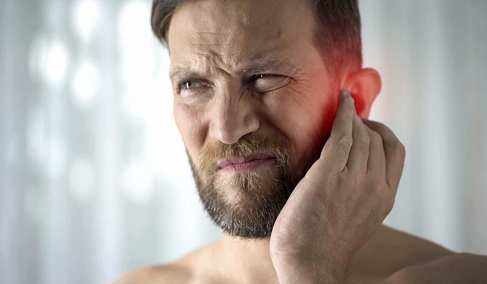 Ontstoken oor door mastoïditis met roodheid en pijnlijke zwelling.
