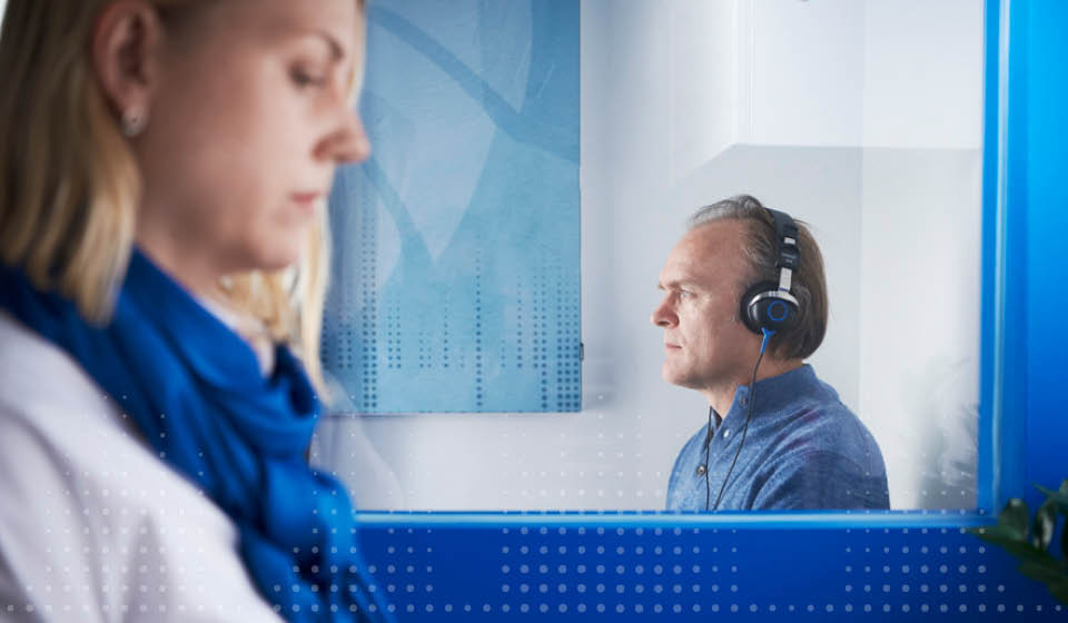 Gehoortest uitgevoerd in een audiocabine met een audicien en een cliënt.