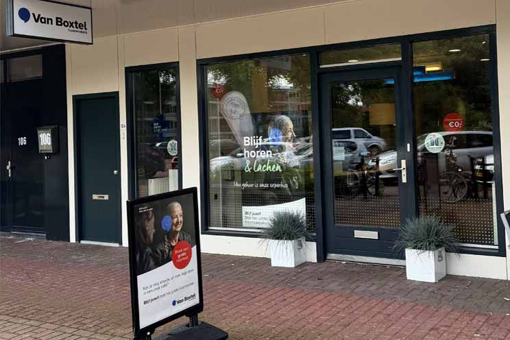 Hoorzorgwinkel van Audika in Emmeloord met een straatbord en etalage met slogan 'Blijf horen & lachen'.