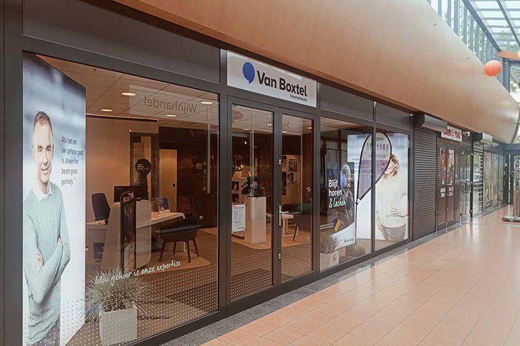 Audika hoorwinkel in het winkelcentrum van Venlo met promotieposters en glazen gevel.