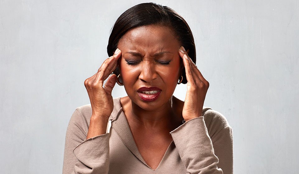 Vrouw met klachten van tinnitus en oorsuizen, houdt haar handen tegen haar hoofd.