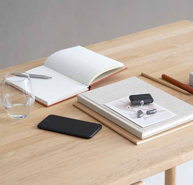 Afbeelding van gehoorapparaten die op een stapel met boeken ligt