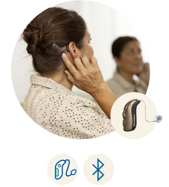 Bernafon Entra hoortoestel met Bluetooth-connectiviteit, gedragen door een vrouw die het apparaat aanpast.