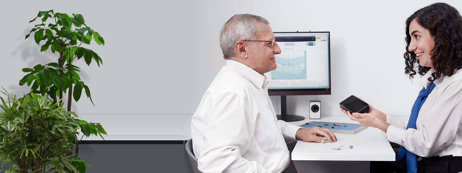 Man bij audicien tijdens hoormeting met audiogram op computerscherm.