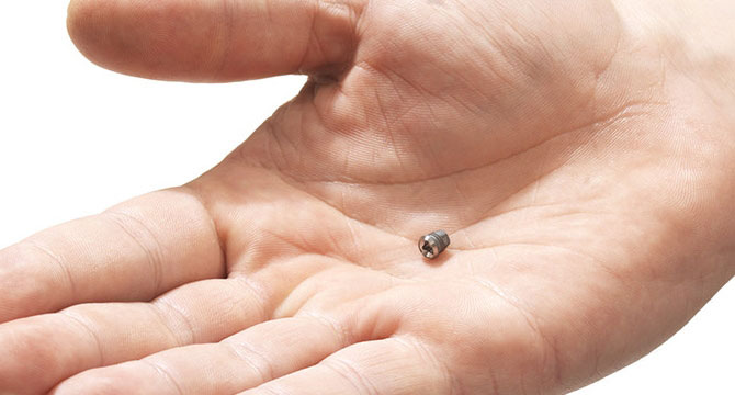 Een superkleine, onzichtbare gehoorapparaat ligt stil in een open handpalm, gehuld in een lichte, neutrale omgeving, mogelijk een audiologiekliniek gericht op gehoorzorg zoals Audika.