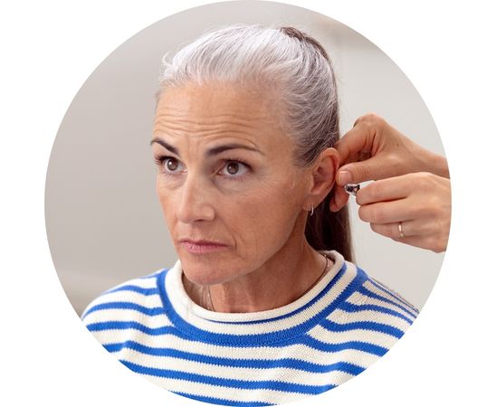 Een vrouw die een gehoorapparaat in krijgt