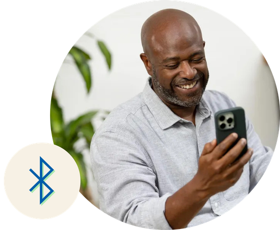 Een man met zijn telefoon in zijn hand die hem verbind met zijn hoortoestellen door bluetooth