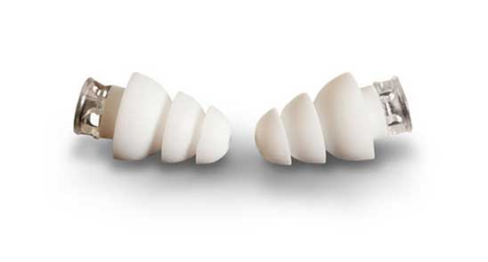 Twee witte, spiraalvormige gehoorbeschermers liggen tegenover elkaar op een witte achtergrond. Ze zijn gemaakt van flexibel materiaal en hebben transparante uiteinden, geschikt voor gehoorcomfort en demping.