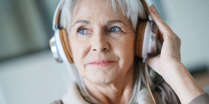 Kobieta w średnim wieku korzysta ze słuchawek podczas badania słuchu.