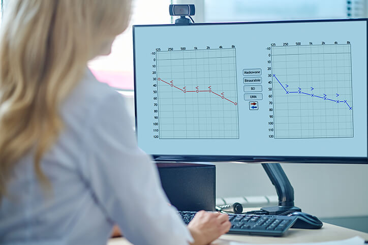 Specjalista ds. protetyki słuchu przegląda wyniki audiogramu na ekranie komputera.