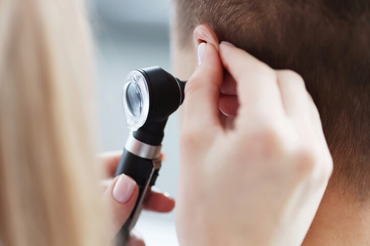 Specjalista używa otoskopu do badania ucha pacjenta.
