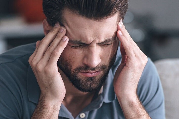 Mężczyzna trzyma się za głowę, odczuwając dyskomfort związany z problemami ze słuchem.