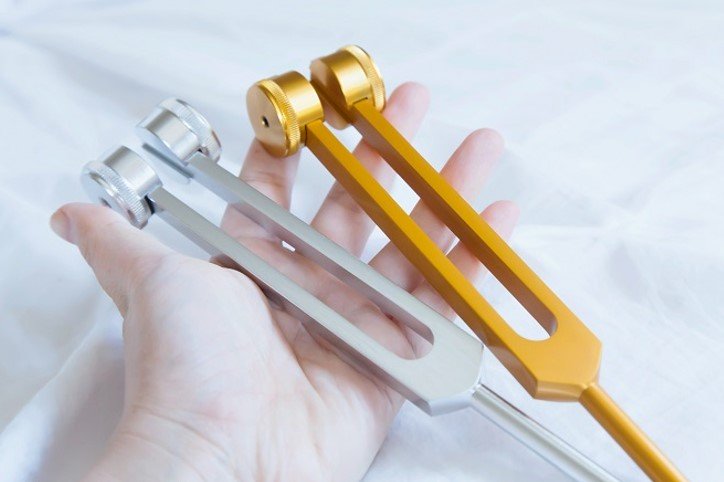 Metalowe stroiki w dłoni, używane podczas diagnostycznych badań słuchu.