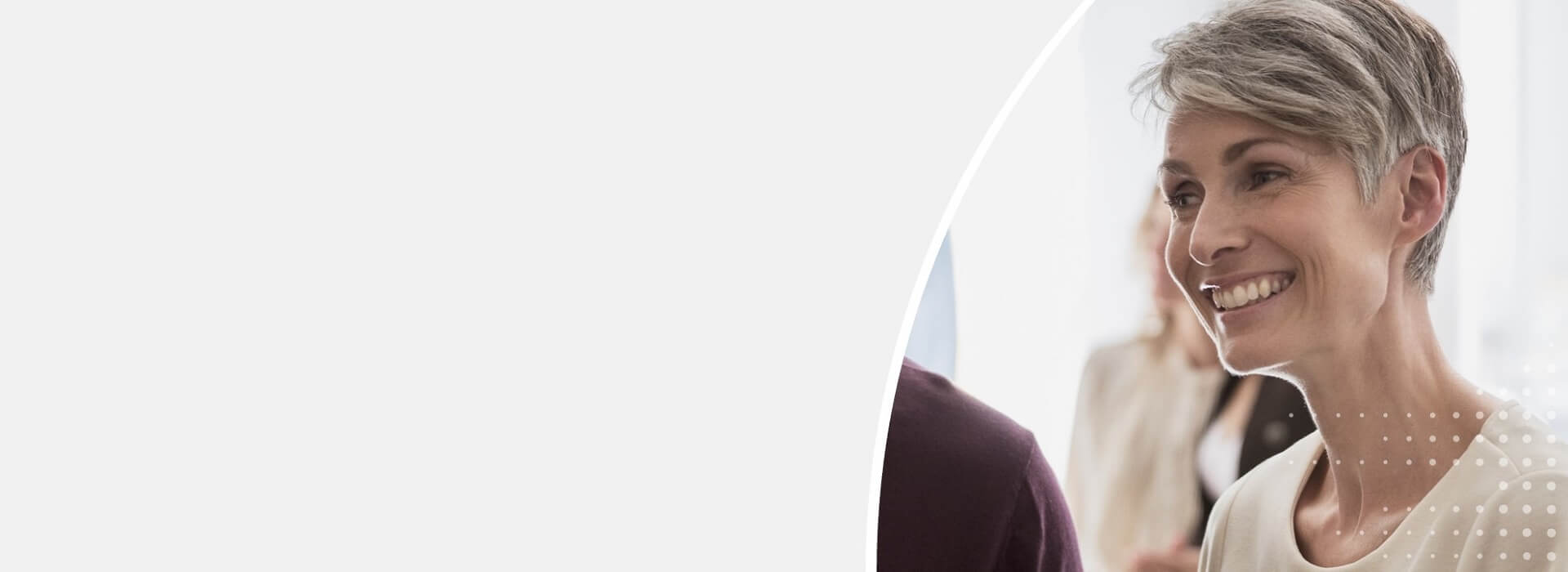 Kobieta korzystająca z aparatów słuchowych uczestniczy w spotkaniu, uśmiecha się i prowadzi rozmowę.