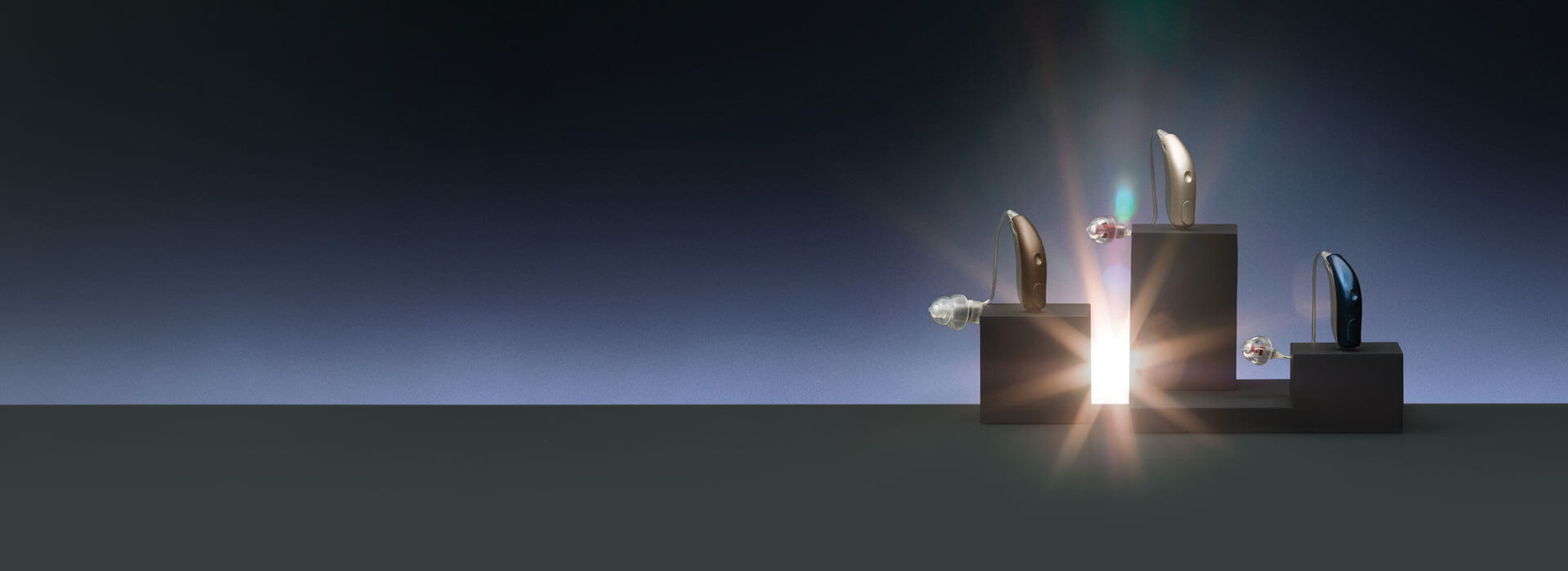 Kilka modeli aparatów słuchowych producenta Bernafon stoi na czarnym ekspozytorze.