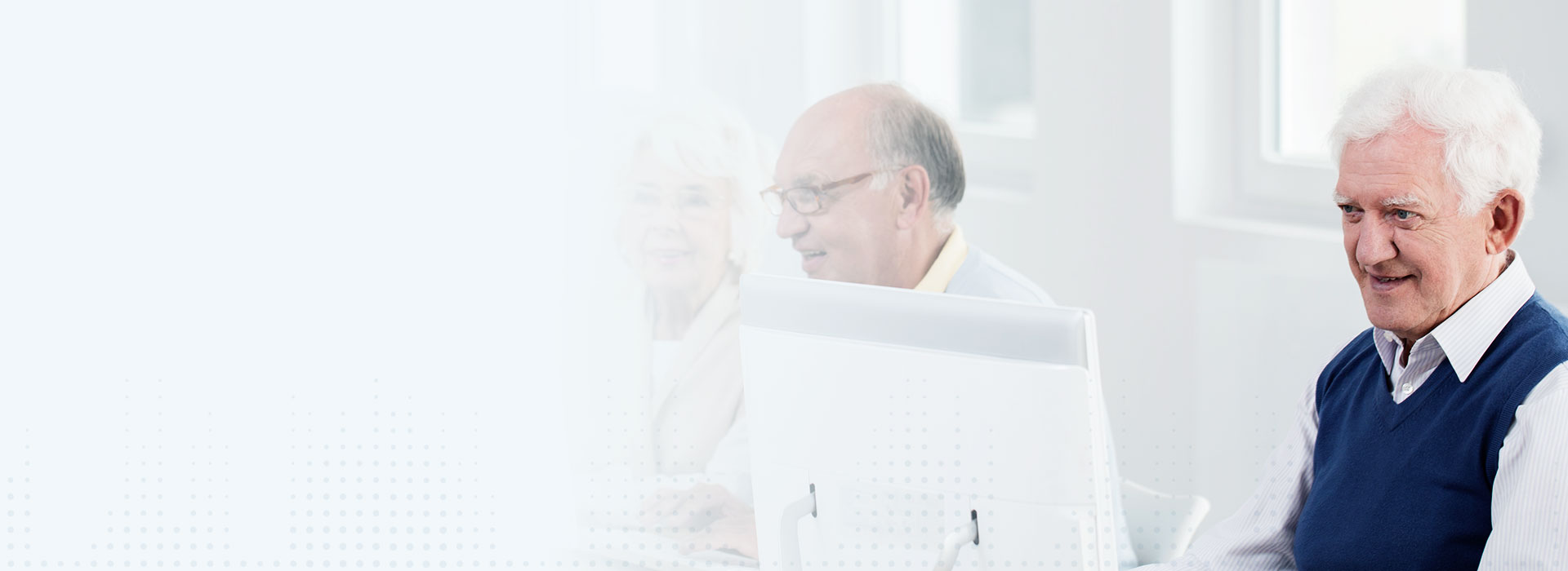 Starszy mężczyzna przy komputerze rozważający zakup wkładek dousznych.