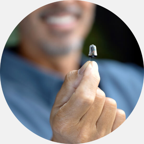 Nowoczesny aparat słuchowy trzymany w dłoni użytkownika.