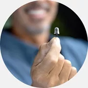 Nowoczesny aparat słuchowy trzymany w dłoni użytkownika.