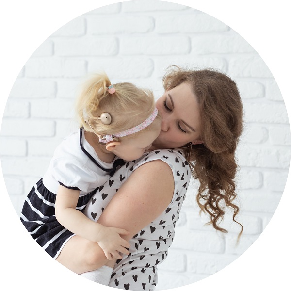 Matka trzyma na rękach dziecko z implantem ślimakowym.