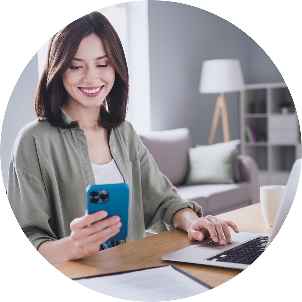 Kobieta korzysta z telefonu i laptopa, przygotowując się do rekrutacji w Audika.