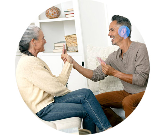 Kobieta i mężczyzna grają w karty, ciesząc się lepszą jakością życia dzięki badaniu słuchu online.