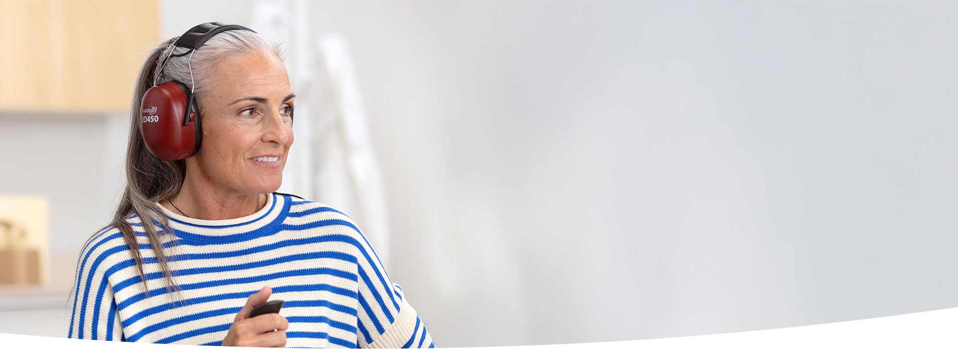 Kobieta w słuchawkach ochronnych przeprowadza badanie słuchu w gabinecie Audika.