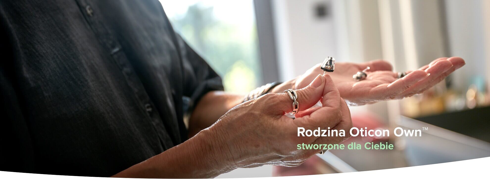Rozpoznaj personalizowany aparat słuchowy Oticon Own™ prezentowany w dłoniach.
