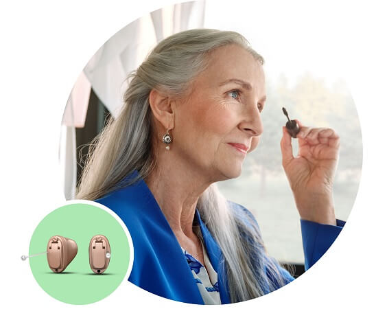 Aparat słuchowy douszny Oticon Own™ prezentowany przez elegancką kobietę.
