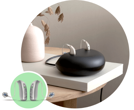 Aparat słuchowy Oticon Zircon™ z ładowarką na eleganckim stoliku.