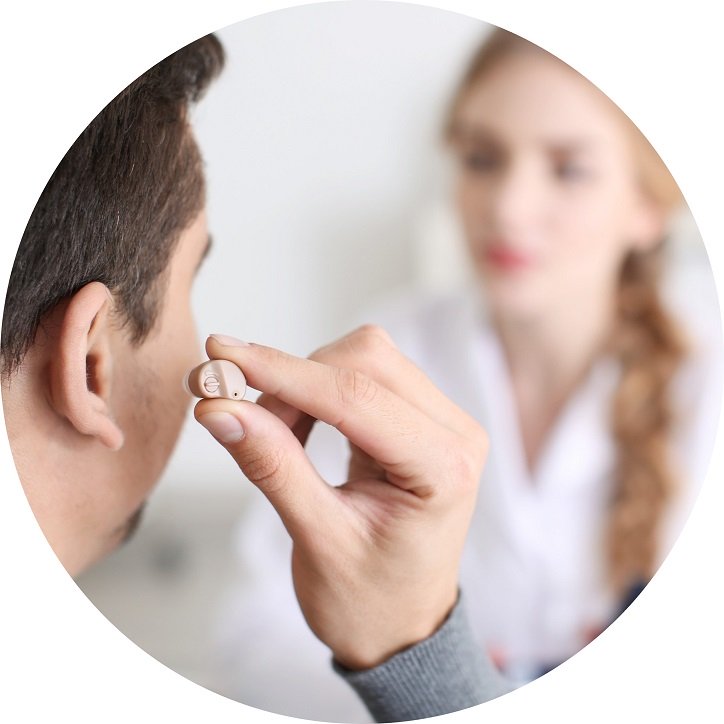 Mężczyzna testuje douszny aparat słuchowy podczas konsultacji w gabinecie protetyka słuchu.