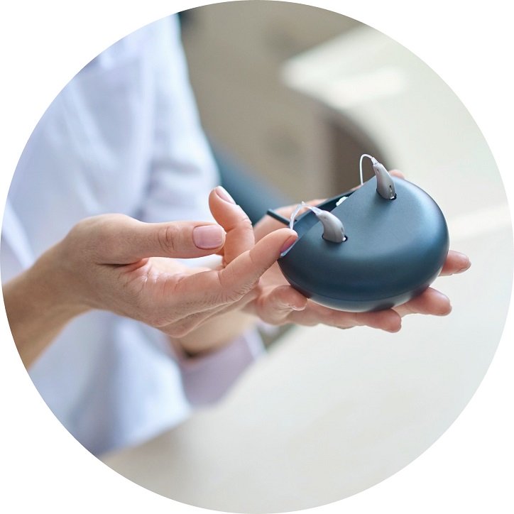 Prezentacja nowoczesnych aparatów słuchowych z ładowarką w dłoniach kobiety.