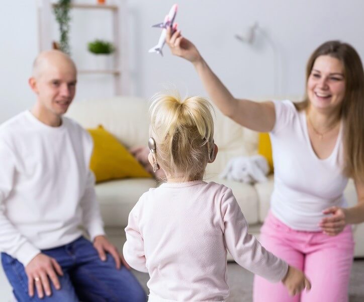 Rodzina spędza czas razem w domu, bawiąc się z dzieckiem z implantem ślimakowym.