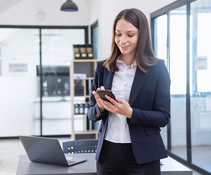 Specjalistka ds. opieki słuchu w biurze, korzystająca z telefonu i laptopa.