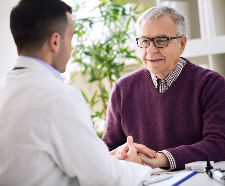 Mężczyzna rozmawia z protetykiem słuchu podczas wizyty w gabinecie.