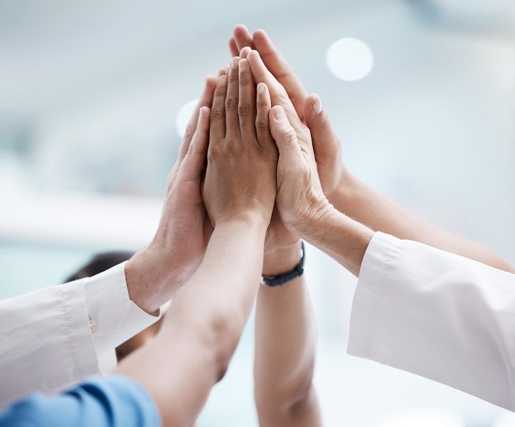 Zespół specjalistów celebruje sukces, przybijając piątki.