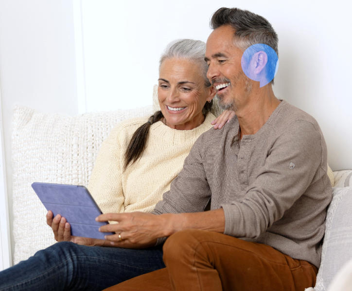 Starsza para przegląda tablet, zdobywając informacje o aparatach słuchowych.