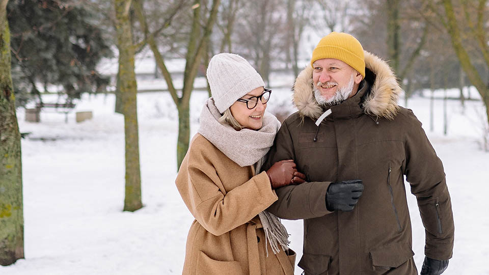 Bild på ett par som går i snön genom en park