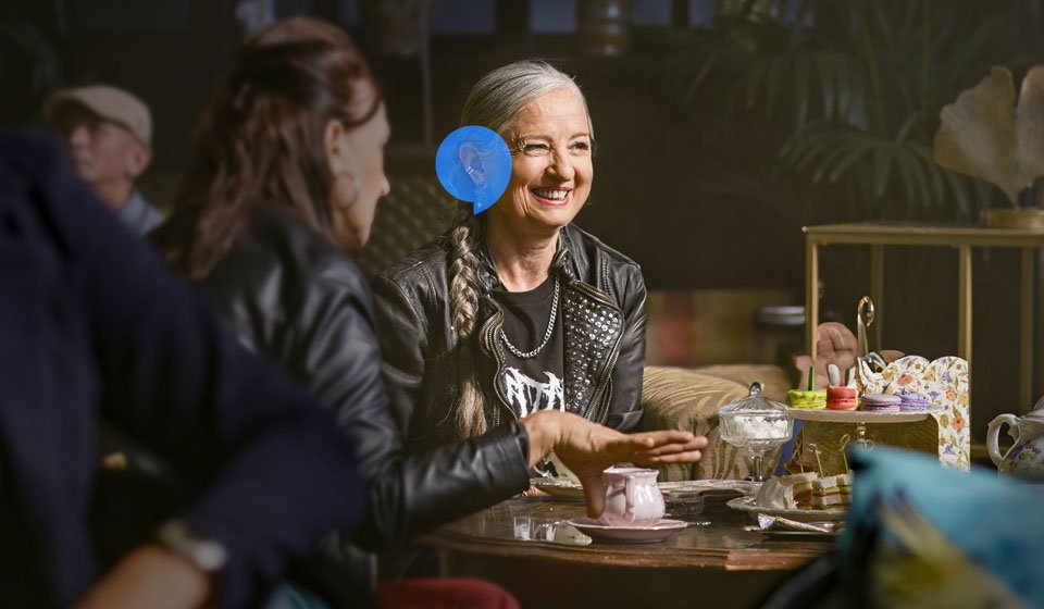  Kvinna med hörapparat sitter och samtalar i en trivsam miljö i Stockholm