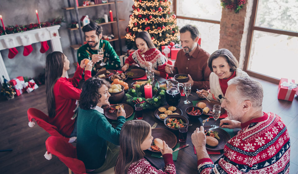  En familj som samlas runt ett julbord och använder kommunikationstips från Audika för att skapa en trevlig samtalsmiljö.