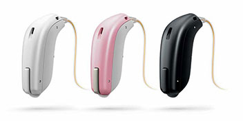  Tre hörapparater i olika färger: vit, rosa och svart, placerade på en vit bakgrund.