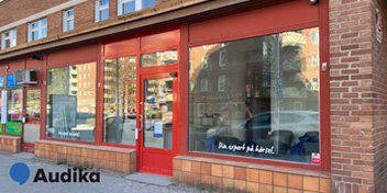  Audikas nya hörselklinik i Huddinge med röd fasad och stora skyltfönster.