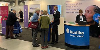  Audikas monter på seniormässa med personal som pratar med besökare