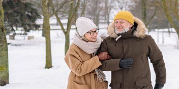 Ett vinterklätt par som promenerar genom en snöig park