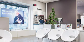  En av Audikas hörselkliniker med väntrum, reception och skylt som frågar: ’Hör du lika bra som förr?’.